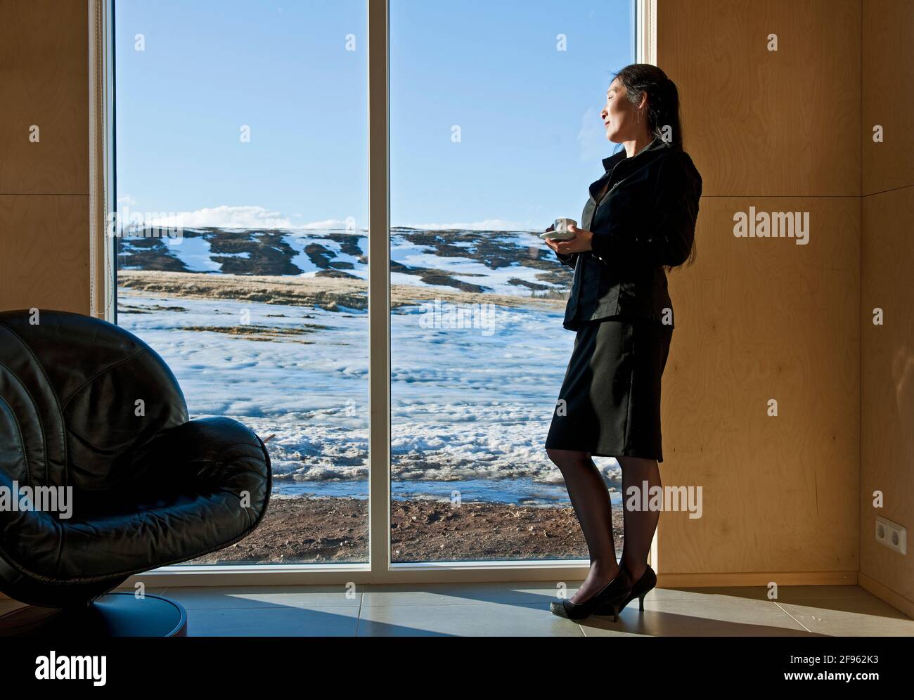 woman in business attire looking out of window from holiday home Stock Photo