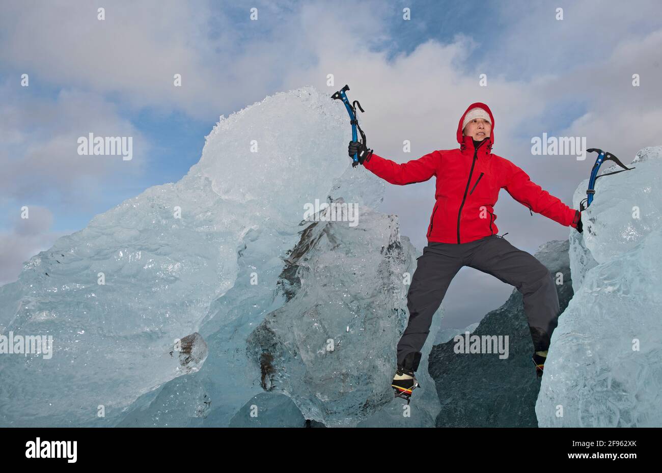 woman climbing iceberg on the south coast of Iceland using ice pick