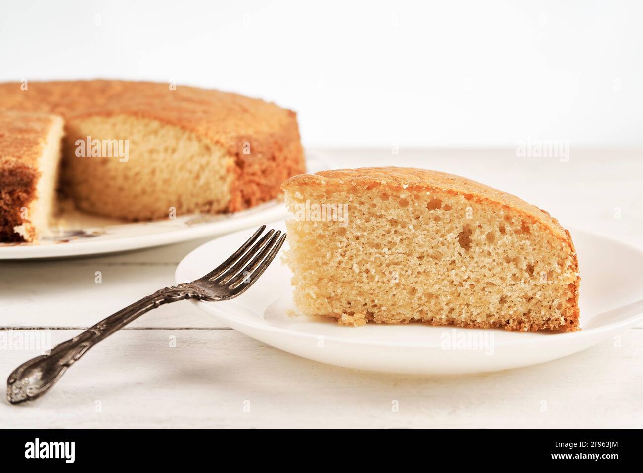 Close up of a slice of homemade sponge cake on a white wooden table Stock Photo
