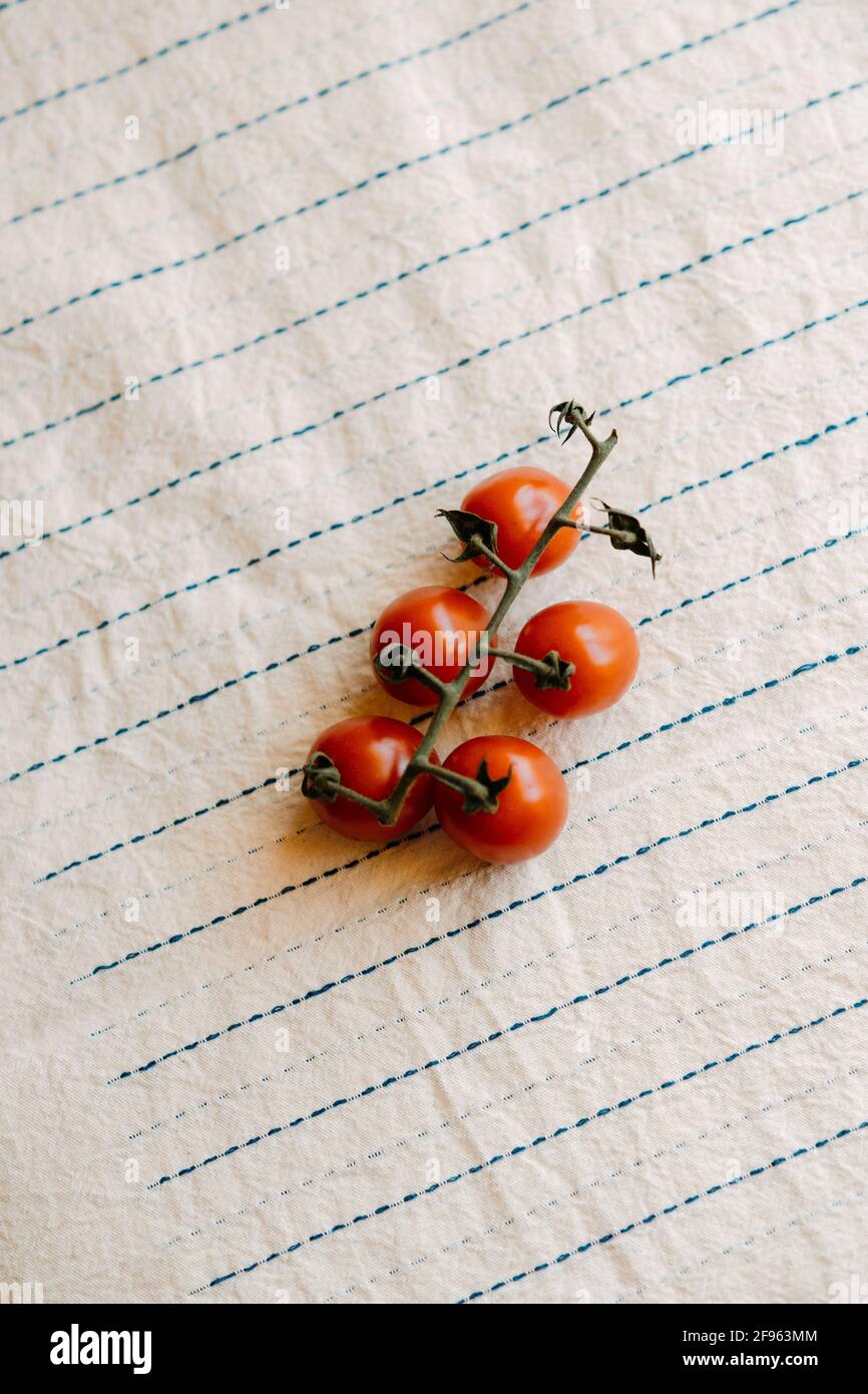Cluster of fresh and organic cherry tomatoes on a rustic white tablecloth Stock Photo