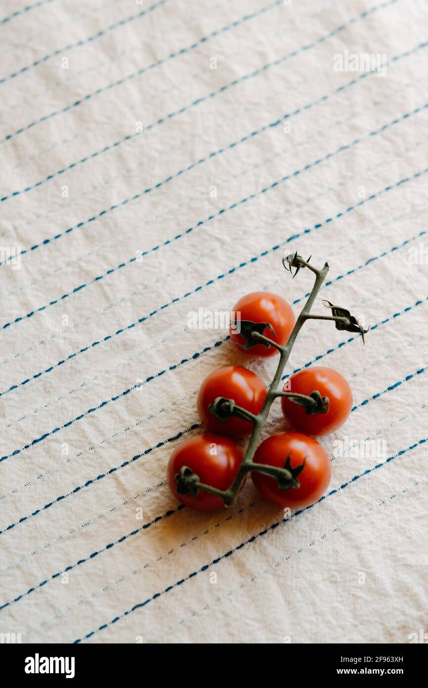 Cluster of fresh and organic cherry tomatoes on a rustic white tablecloth. Copy space Stock Photo