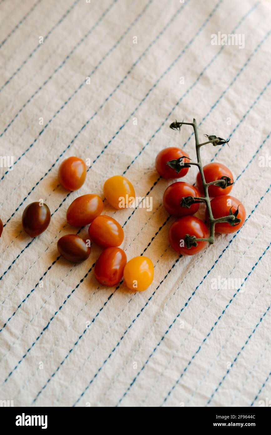 Fresh and organic cherry tomatoes on a rustic white tablecloth.Top view Stock Photo