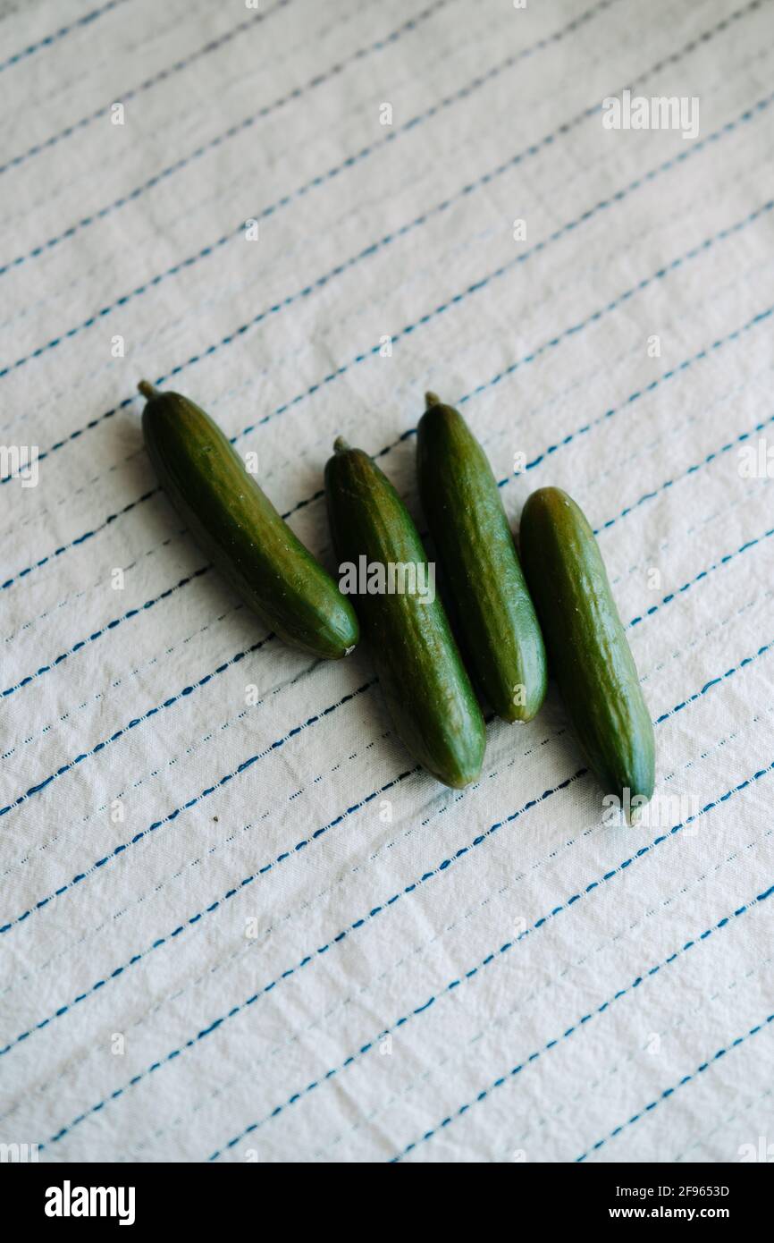 Raw organic mini cocktail green cucumbers on rustic white tablecloth Stock Photo