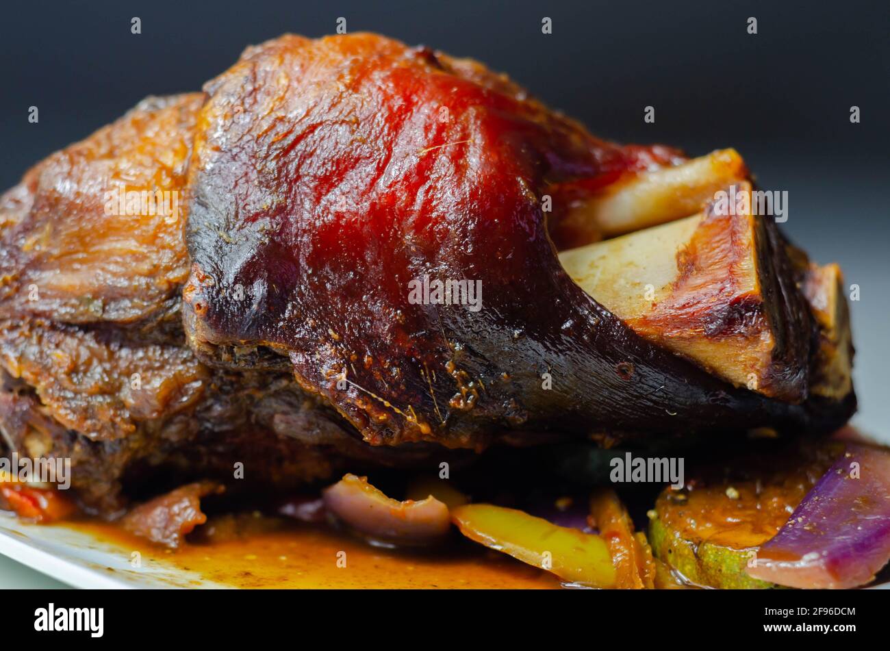 Bacon joint with bone served with grilled vegetables, red and yellow