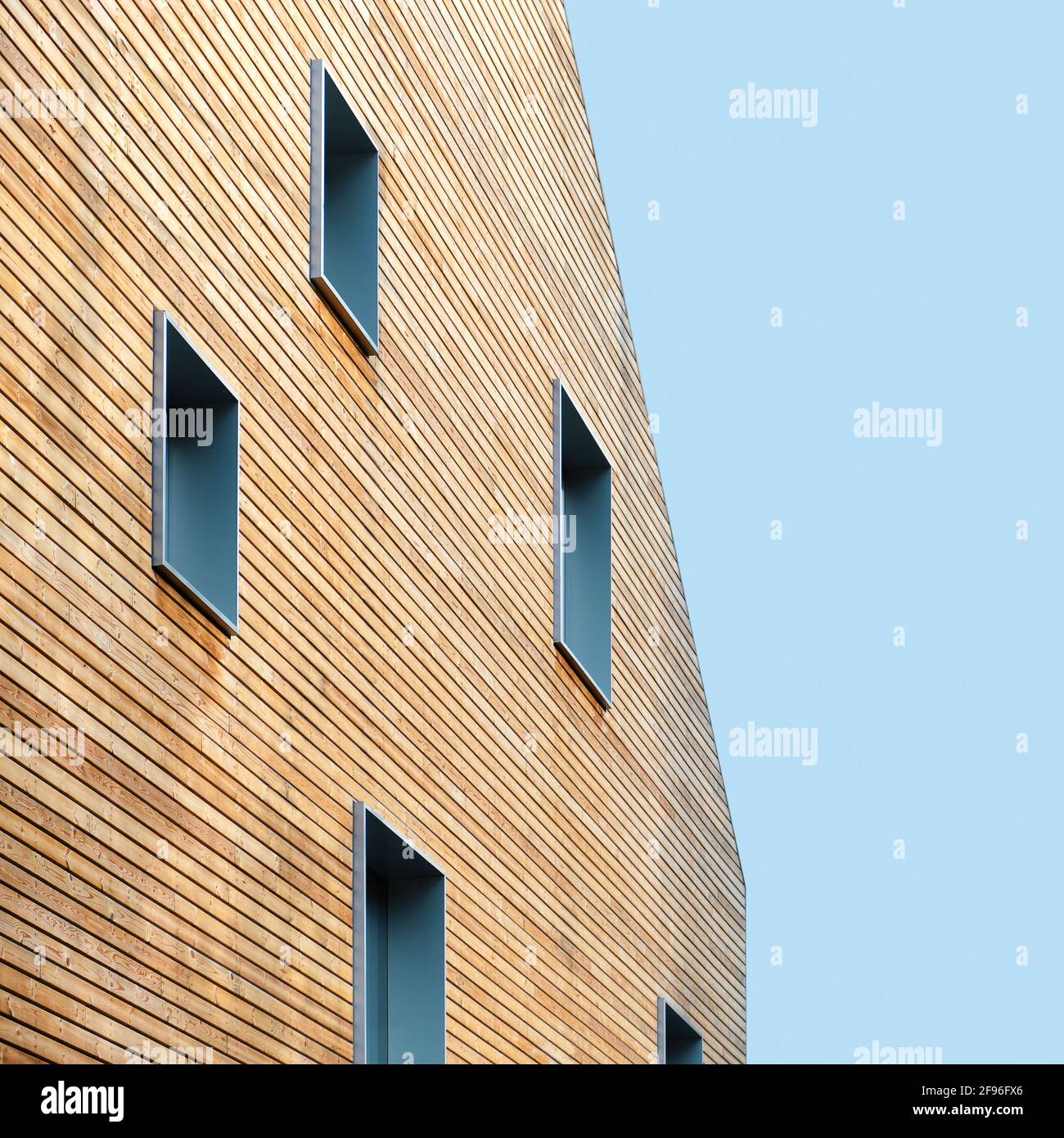 Wooden wall of modern building with windows against blue sky Stock Photo