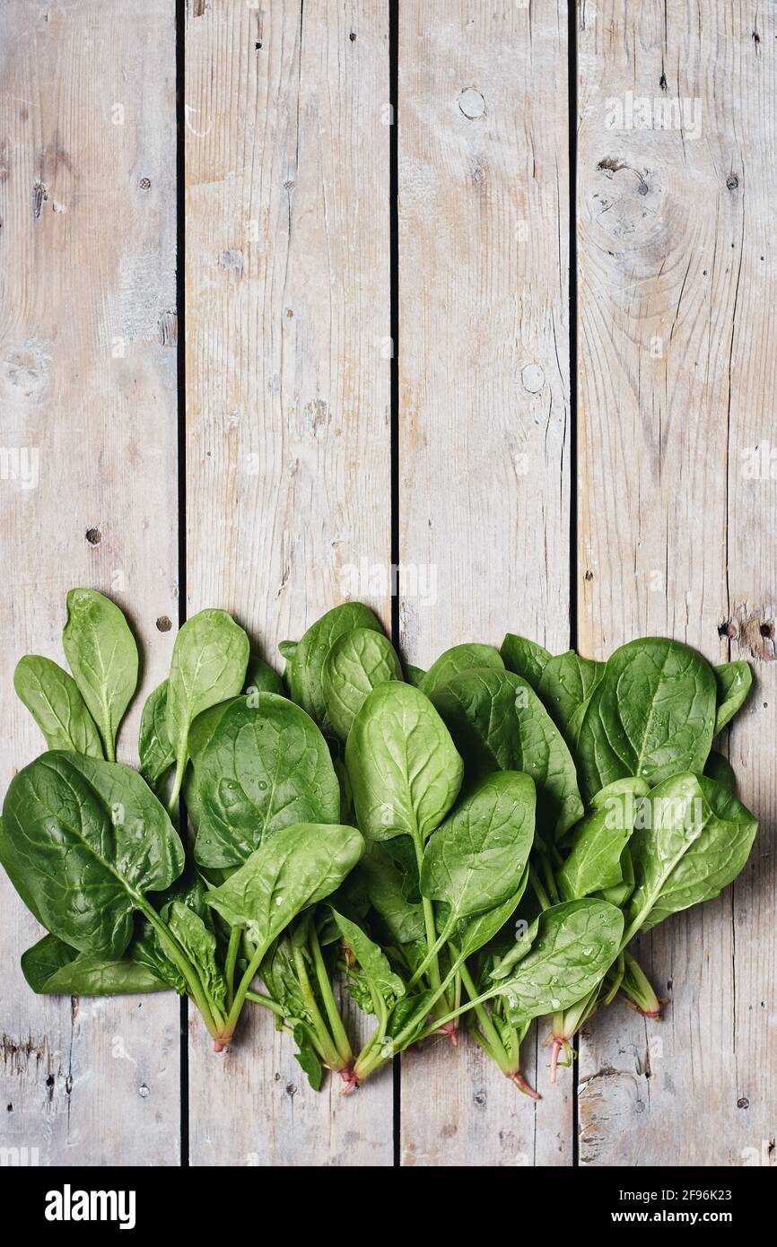 Green spinach leaves on a wooden surface, top view. Stock Photo