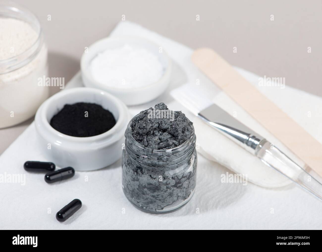 Ingredients for a homemade charcoal facial mask. Charcoal powder, coconut oil, white cosmetic clay. Home beauty concept. Stock Photo