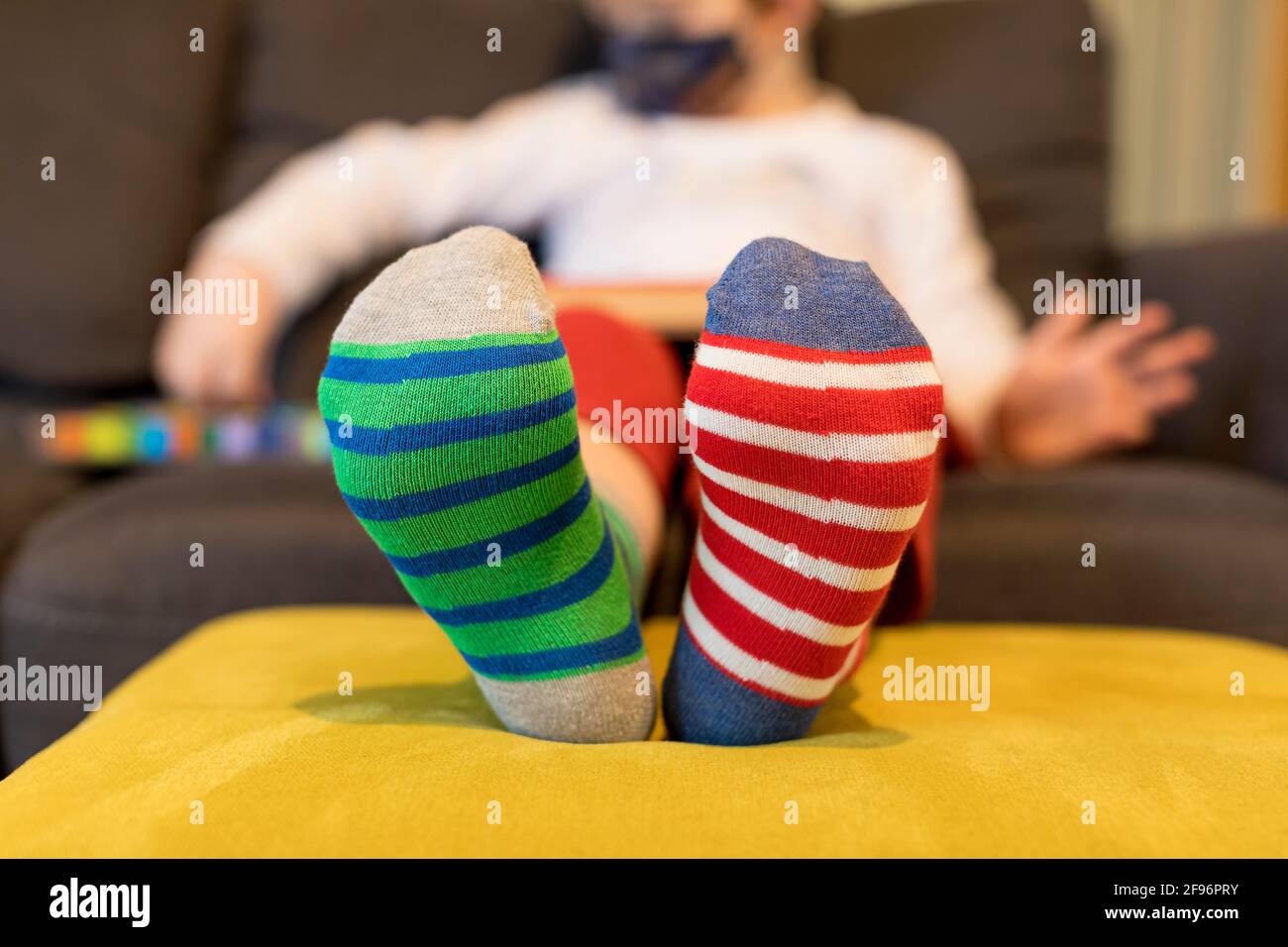 Down syndrome awareness concept. Boy wearing different socks while sitting  on sofa at home. Different socks as symbol of down syndrome. Selective focu  Stock Photo - Alamy