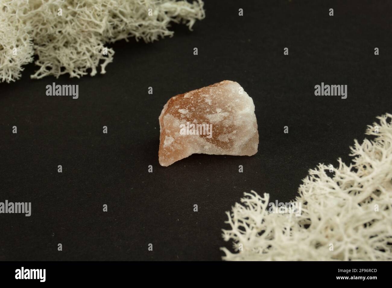 Halite or rock salt from Pakistan. Natural mineral stone on a black background surrounded by moss. Mineralogy, geology, magic, semi-precious stones Stock Photo