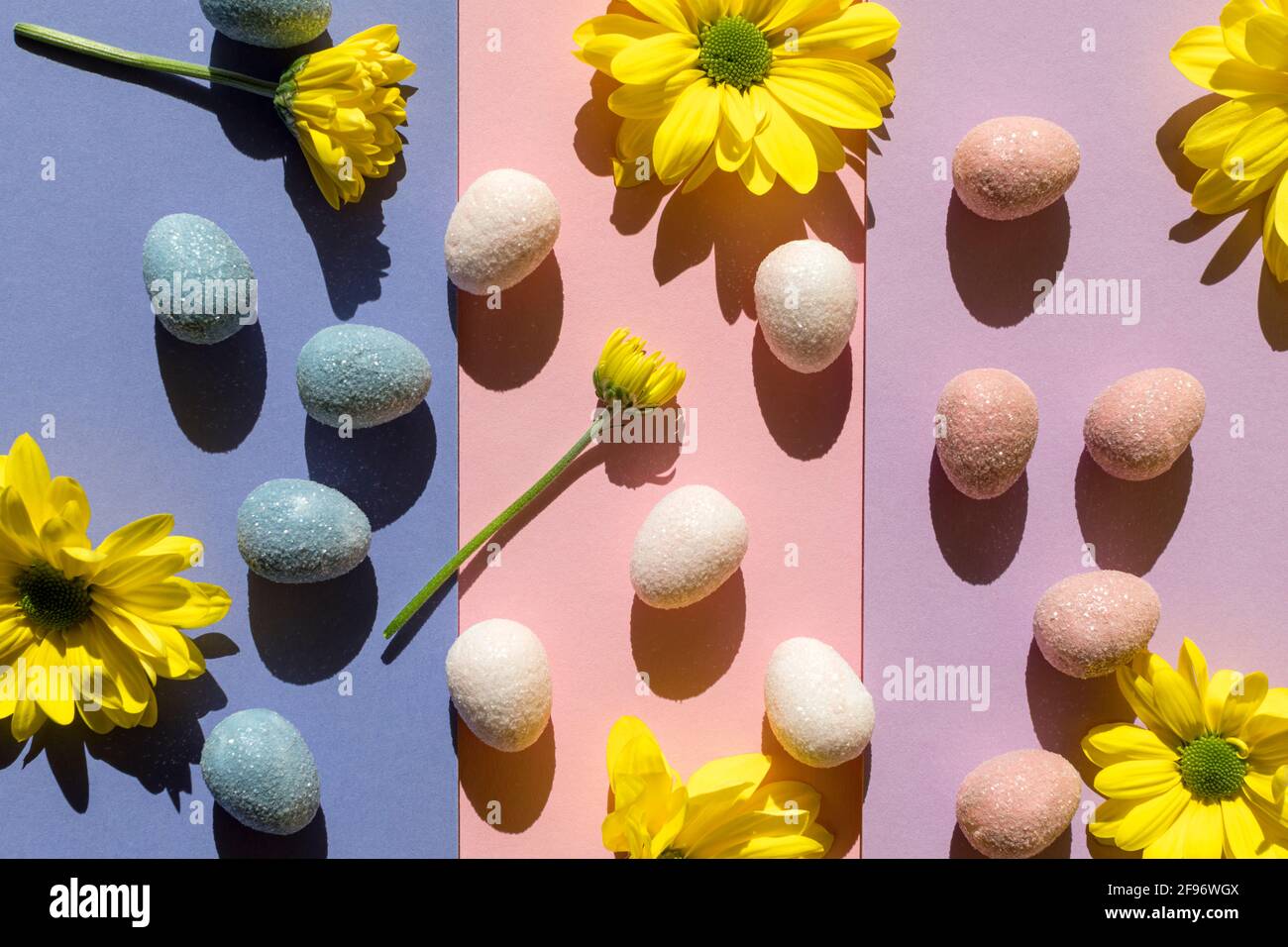 Abstract Easter layout with eggs and yellow flowers with trend summer shadows on colorful background. Minimal spring holiday concept. Flat lay. Stock Photo