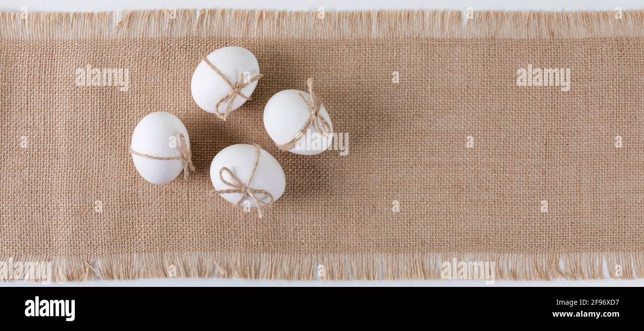 Happy Easter concept. White fresh chicken eggs on linen tablecloth. Simple minimalism banner. Copy space. Flat lay. Stock Photo