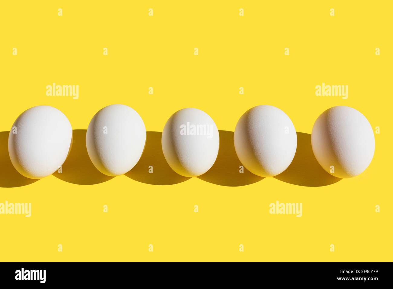 Easter Concept. White fresh eggs in line on Yellow Illuminating background. Minimal food concept. Copy space. Flat lay. Stock Photo