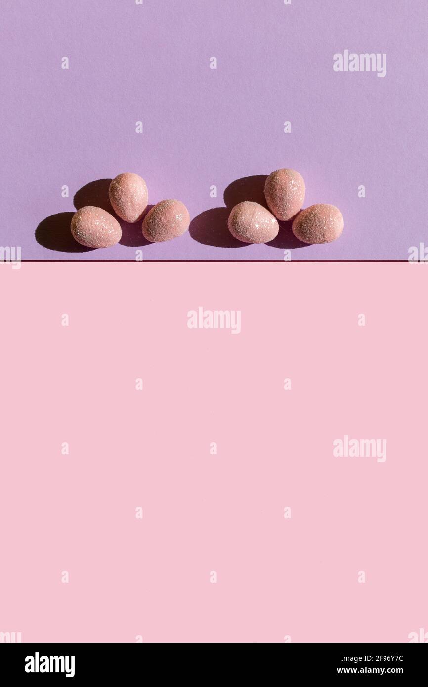 Abstract Easter layout with eggs and trend summer shadows on two tone pastel pink and purple background. Vertical photo. Copy space. Flat lay. Stock Photo