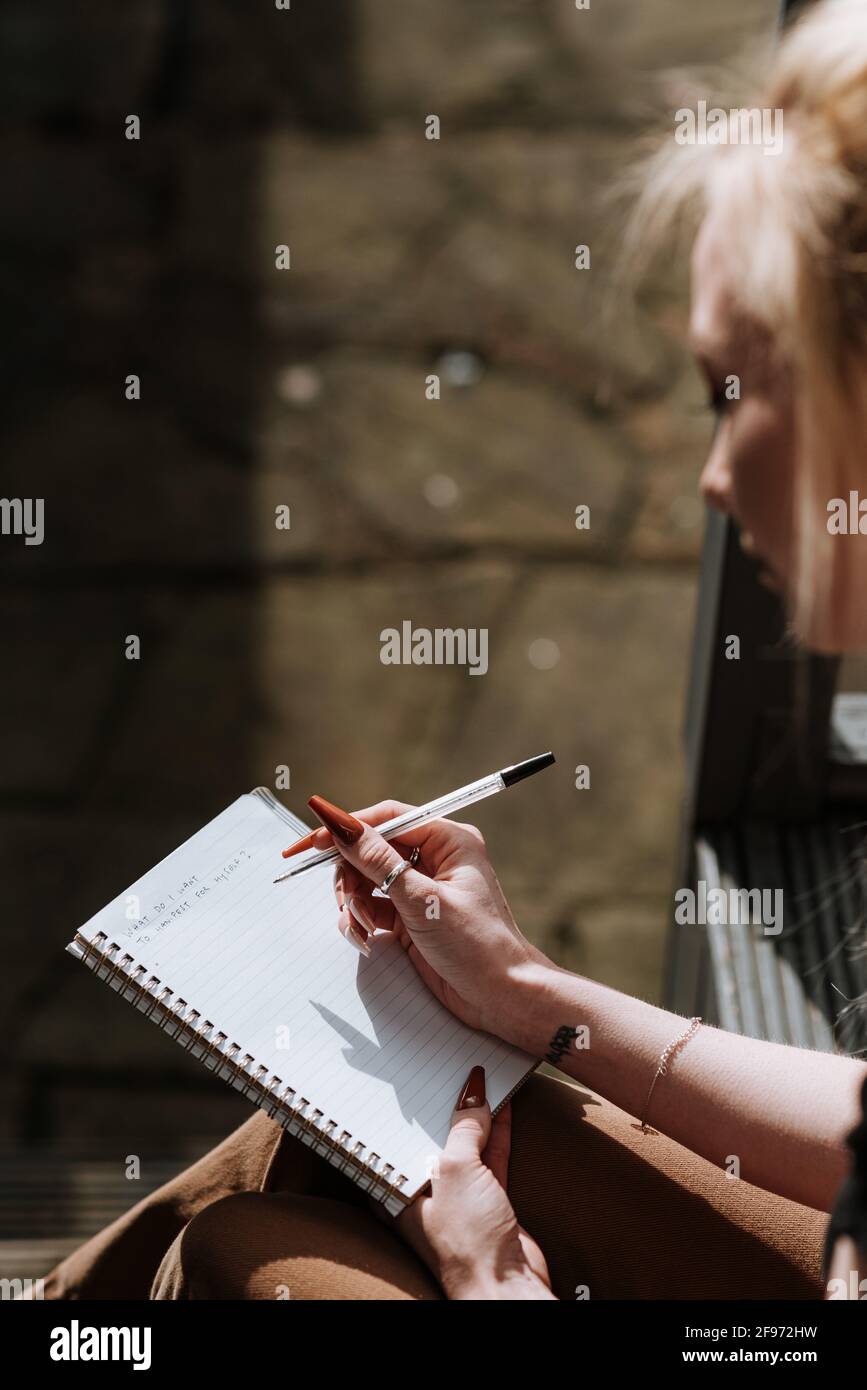 Vertical shot of a female writing some notes in her notebook Stock Photo