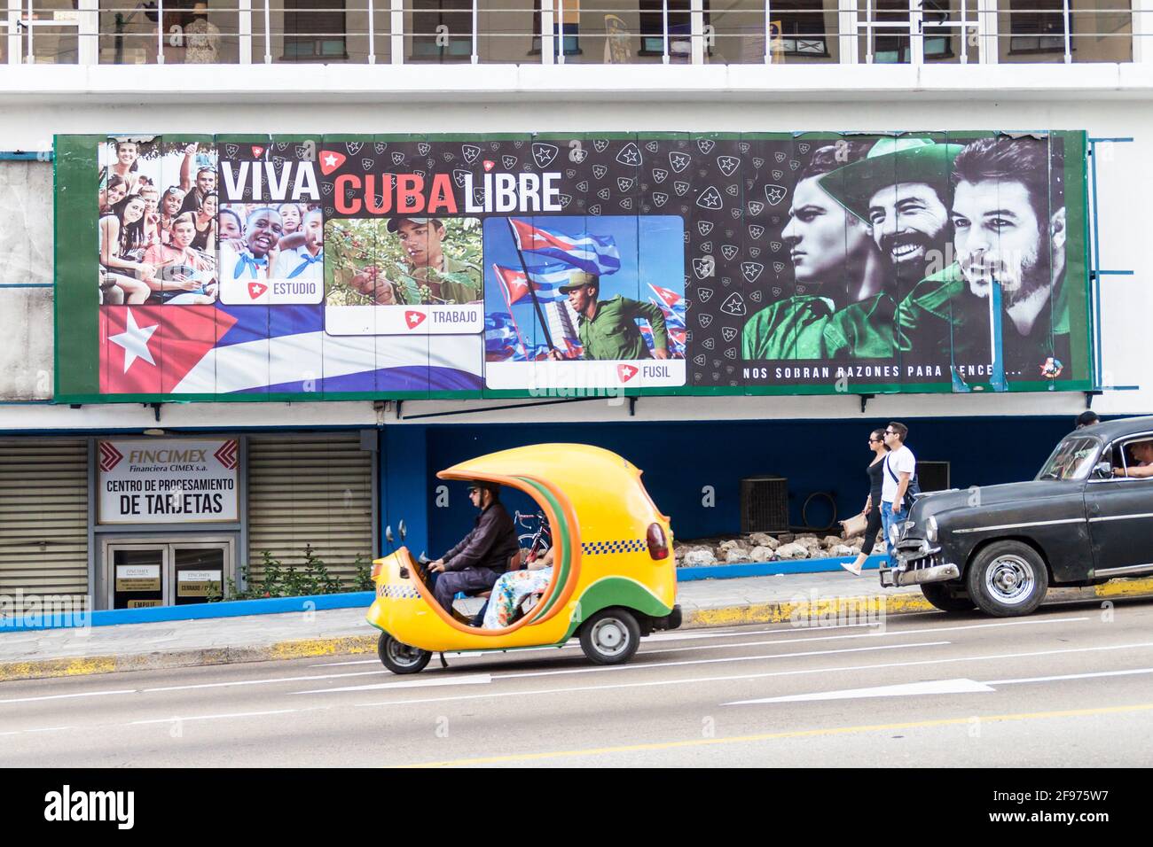 HAVANA, CUBA - FEB 21, 2016: Coco taxi and a propagandistic poster in Vedado neighborhood of Havana. Stock Photo