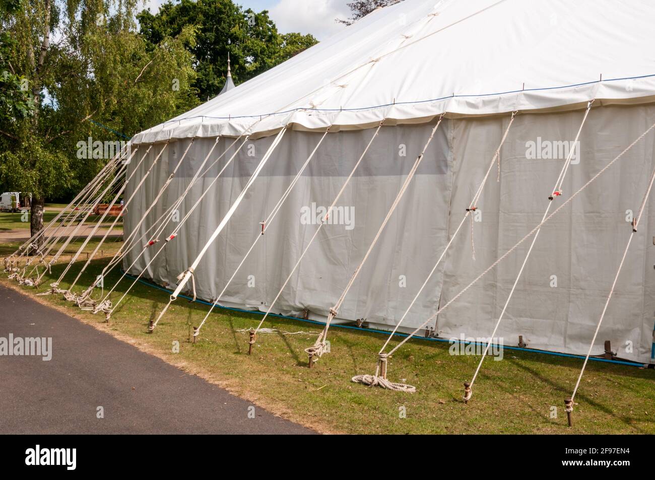 Guy ropes holding up a large tent or marquee erected in a park. Stock Photo