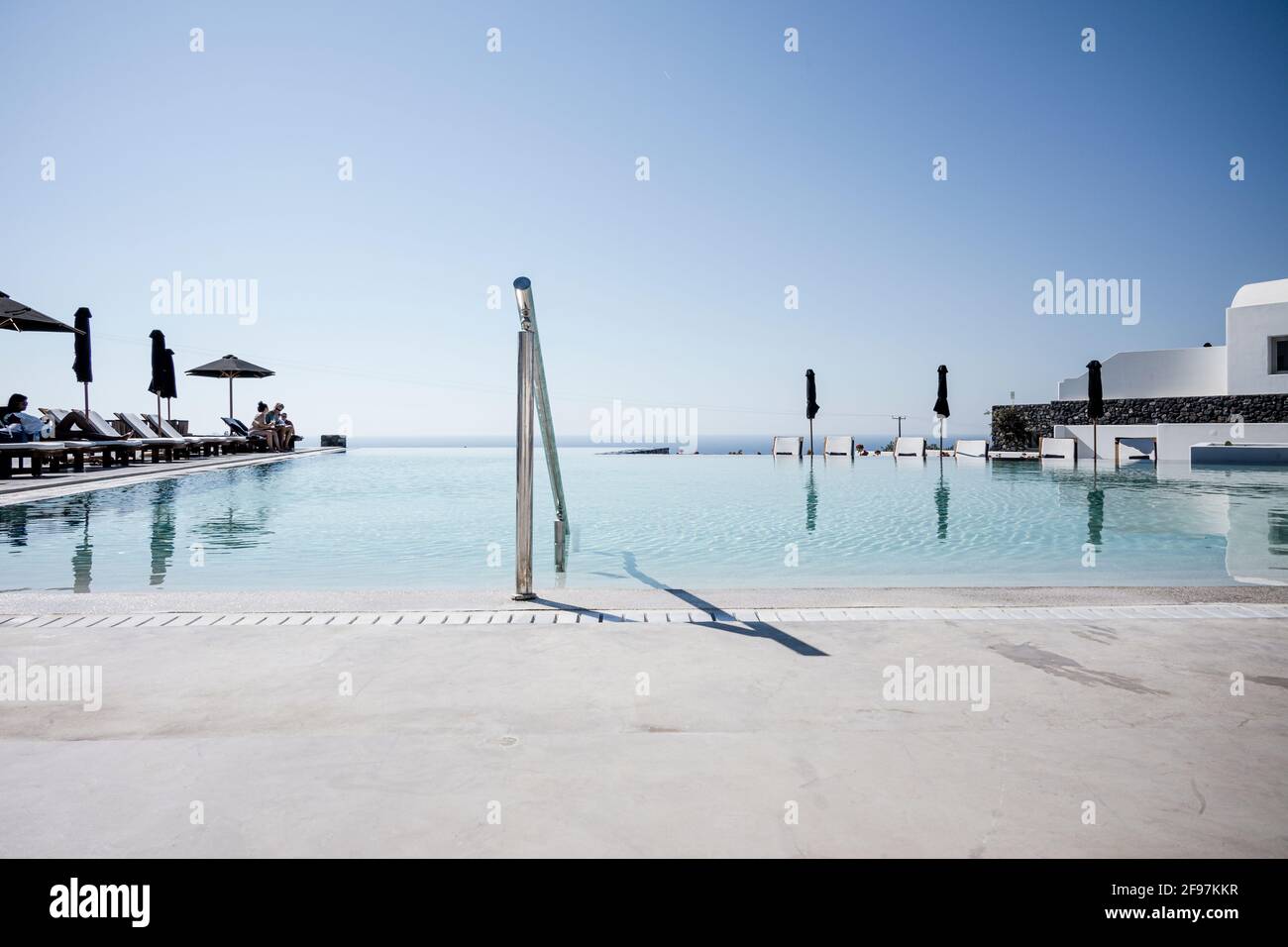 A pool on a resort in Oia on Santorini island with traditional cycladic, white houses and churches with blue domes over the Caldera, Aegean sea, Greece, Stock Photo