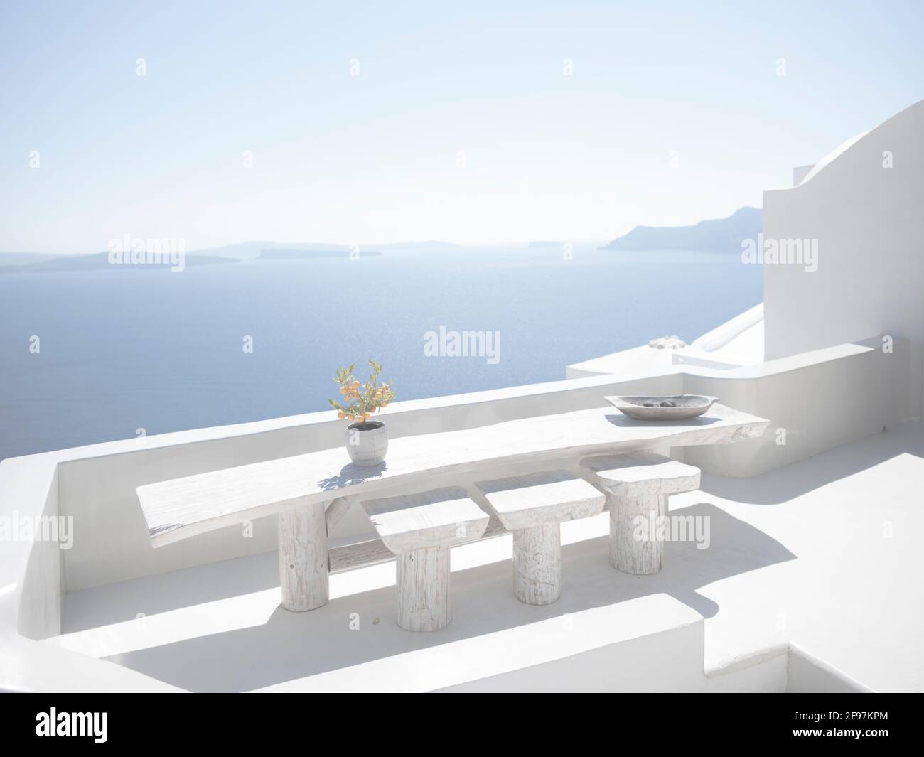 Scenic view of a white balcony with a flower in Oia on Santorini island with traditional cycladic, white houses and churches with blue domes over the Caldera, Aegean sea, Greece, Stock Photo