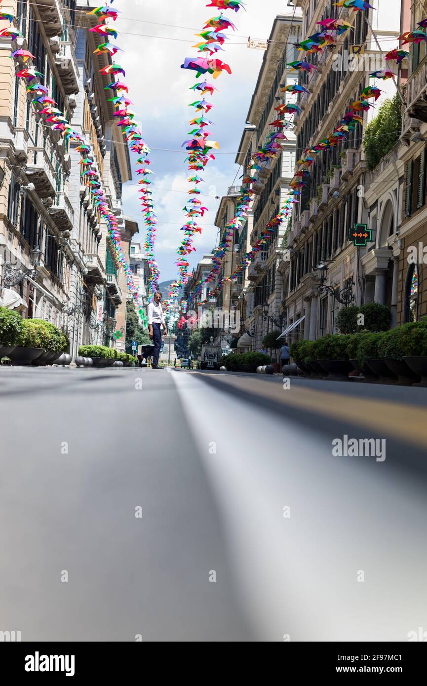 Low positioned shot of multicolored, bright umbrellas hanging between houses along the 'XXV Aprile' street, in the center of Genova (Genoa) city, Italy Stock Photo