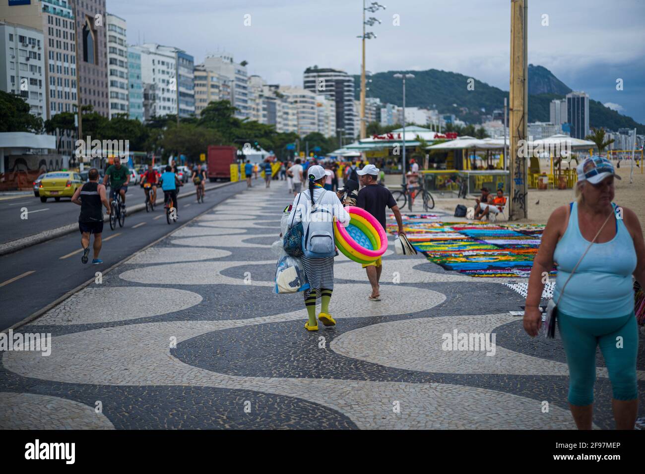 Street seller on the famous Avenida Atlantic with the pattern from Oscar niemeyer at copacabana beach in Rio de Janeiro, Brazil. In the background the famous sugar loaf mountain Stock Photo
