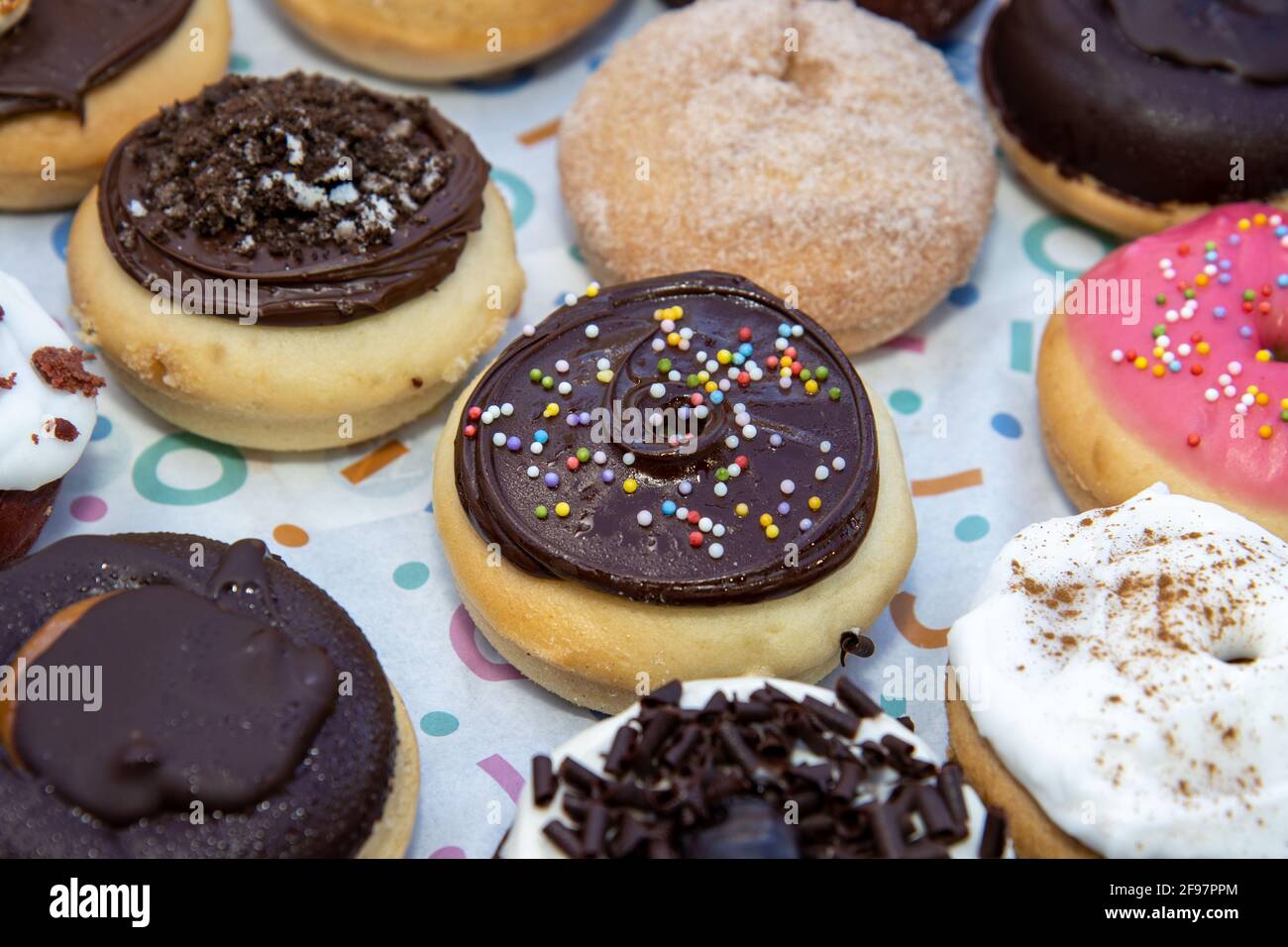A delicious selection of colourful doughnuts including a chocolate one with sprinkles Stock Photo