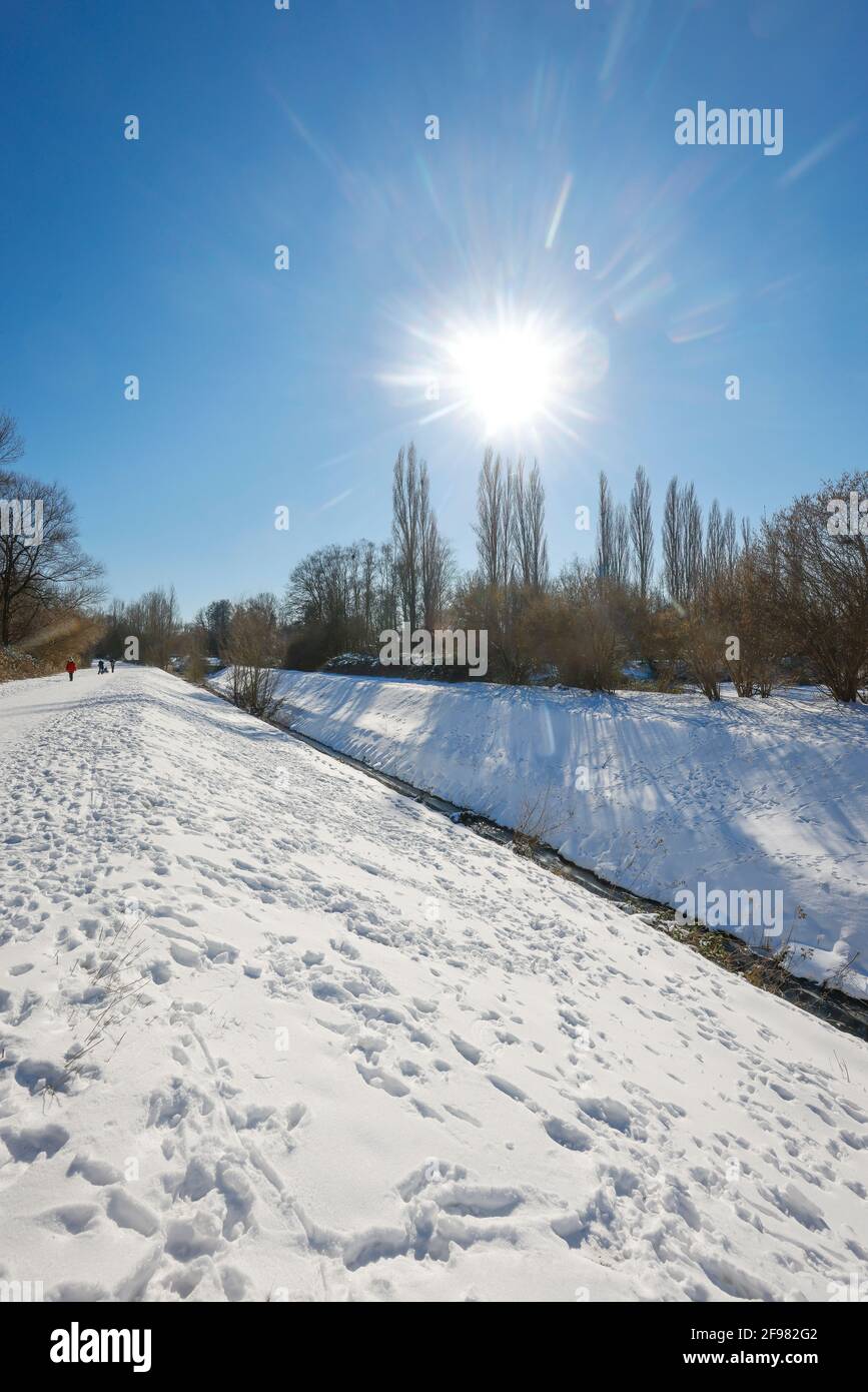 Bochum, North Rhine-Westphalia, Germany - Sunny winter landscape in the Ruhr area, ice and snow at the renatured Hofsteder Bach, the brook has been transformed into a natural body of water, the Hofsteder Bach flows over the Hüller Bach into the Emscher, belongs to the Emscher river system and thus to the Emscher conversion, was previously an open, above-ground wastewater canal, mixed water canal with surface water and wastewater. Stock Photo