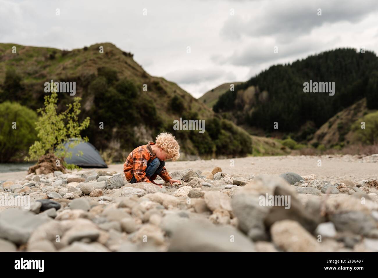 Young curly haired child looking at rock fossils in New Zealand Stock Photo