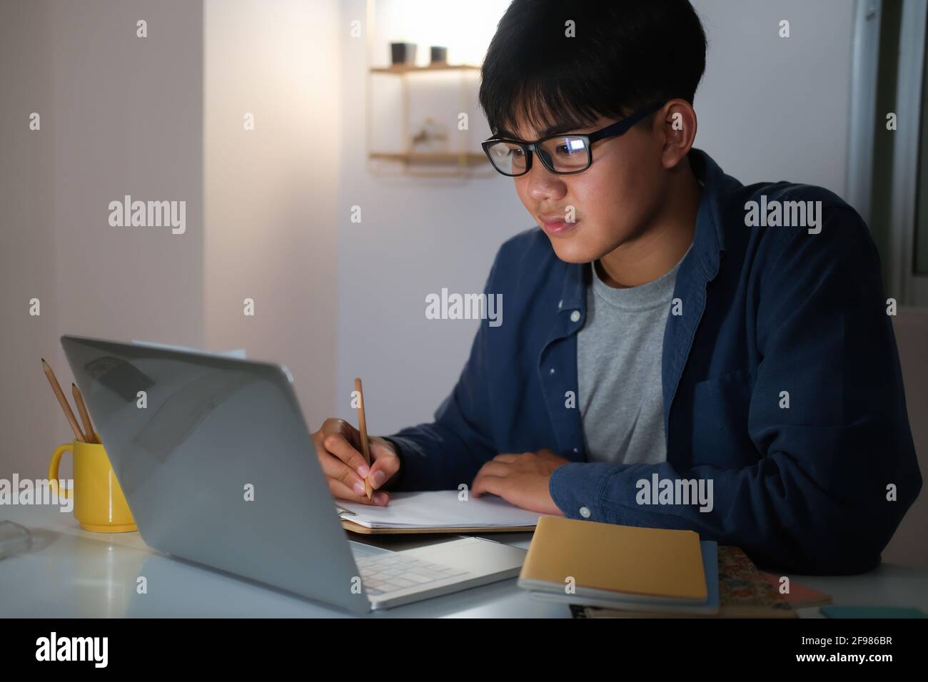 Young collage man learning online at night at his home. Stock Photo