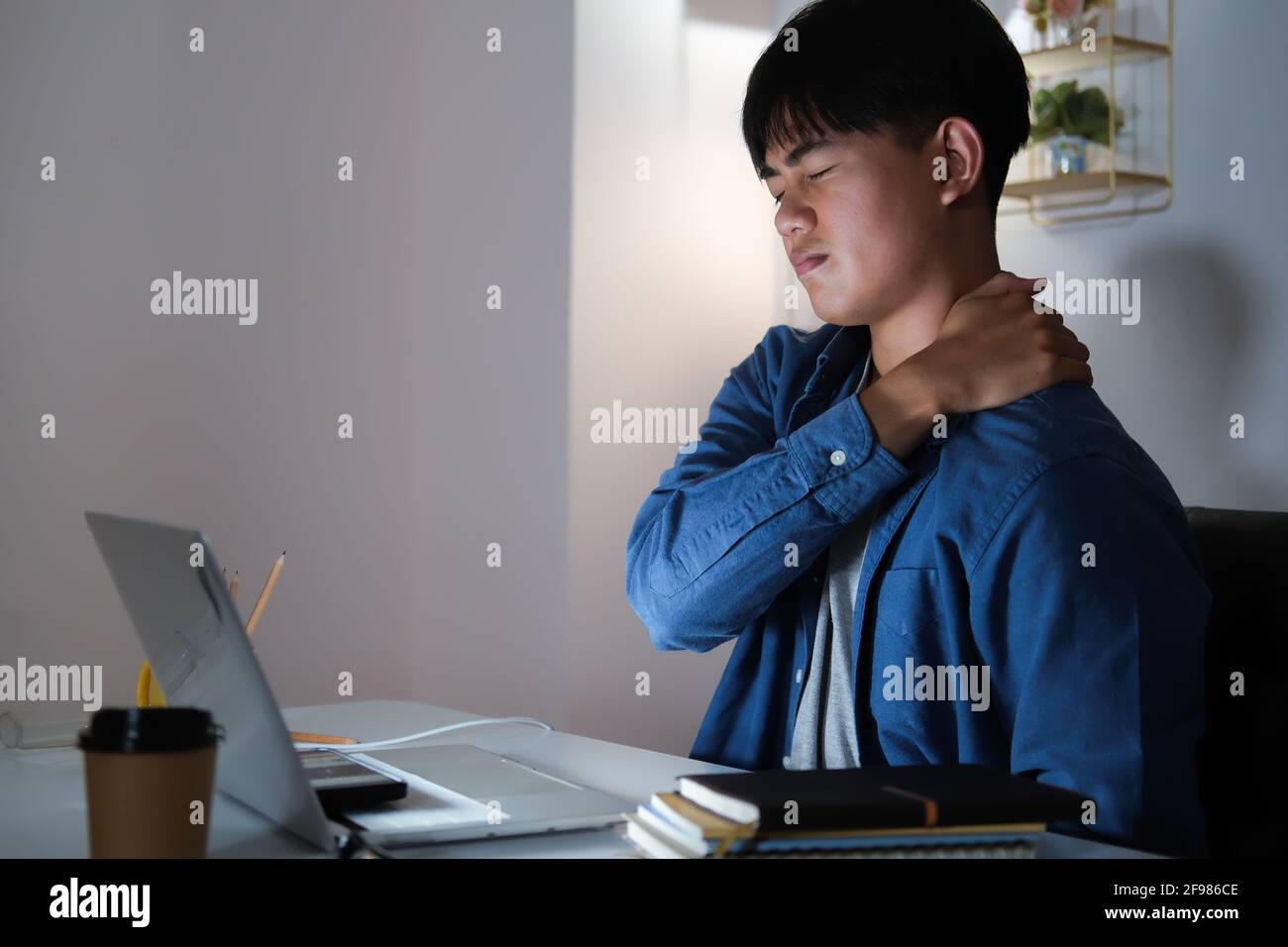 Young man overtime work and feel shoulder and neck pain at home Stock Photo