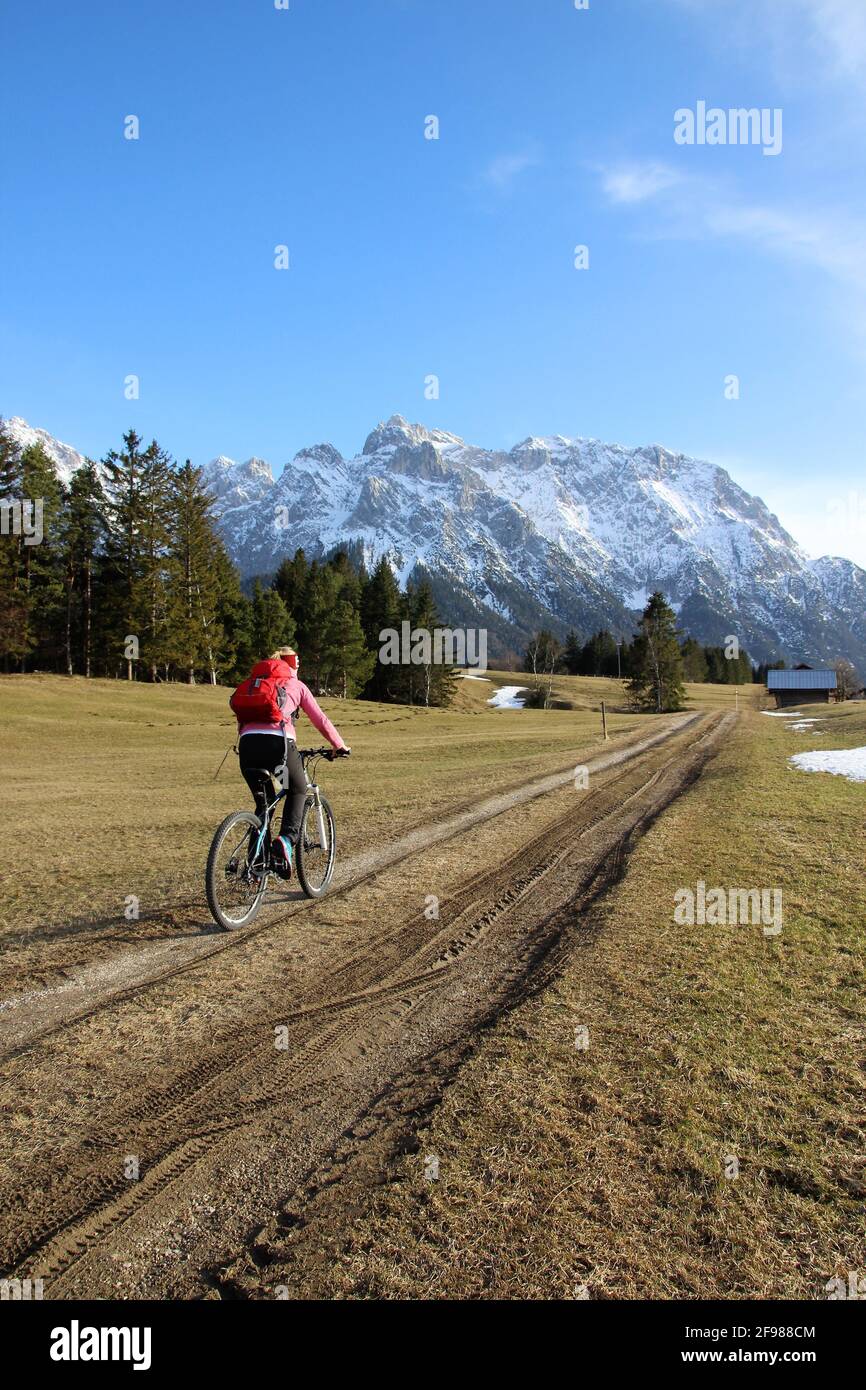 Bicycle tour with a mountain bike in the hump meadows near Mittenwald, Germany, Bavaria, Upper Bavaria, Isar Valley, road, path, bicycle helmet, bicycle, Karwendel Mountains, blue sky Stock Photo