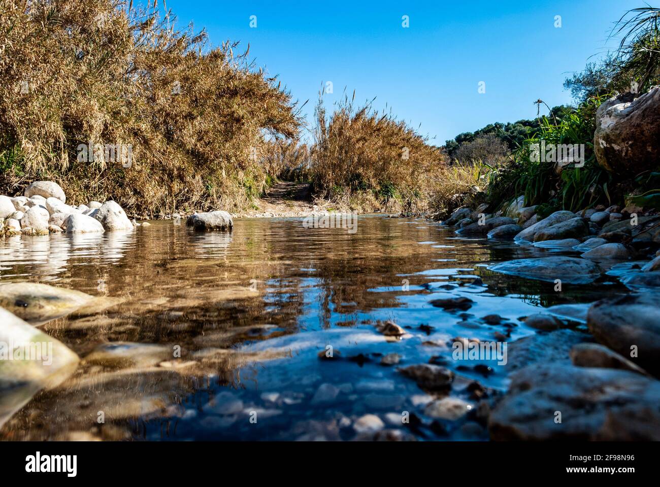 Scenic view of a rocky river with calm water under a clear blue sky ...