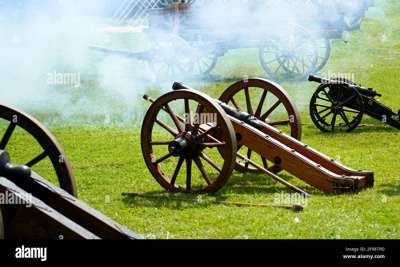 Closeup shot of fired old canons in a field surrounded with white smoke Stock Photo
