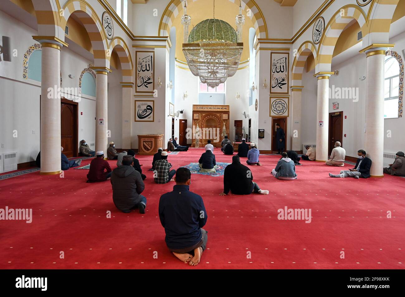 A group of Muslim men gather for early afternoon prayers on the ground ...