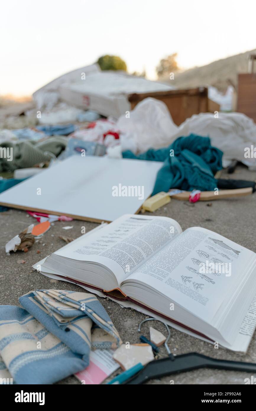 Vertical shot of an open book on the ground in cluttered clothes Stock Photo