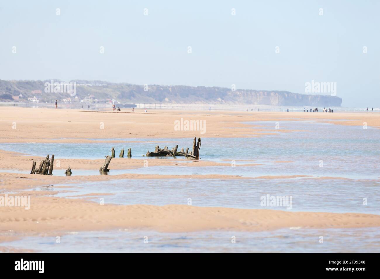 Low tide on Omaha Beach, wreckage protruding from the sand. Stock Photo
