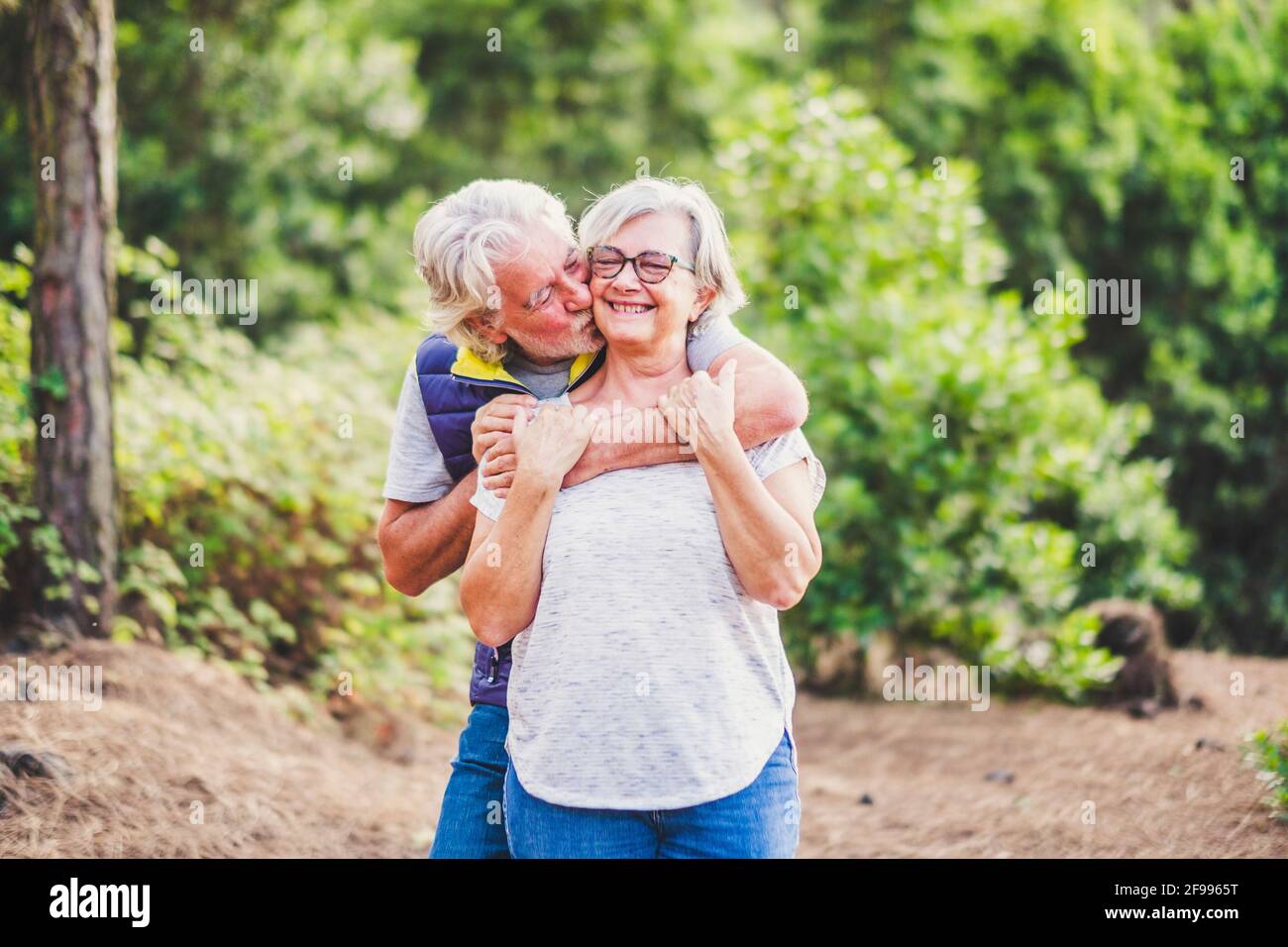 Happiness and love relationship. couple of old people man and woman senior hog and kiss in outdoor park - elderly retired lifestyle and joyful - concept of together forever and outdoor leisure Stock Photo