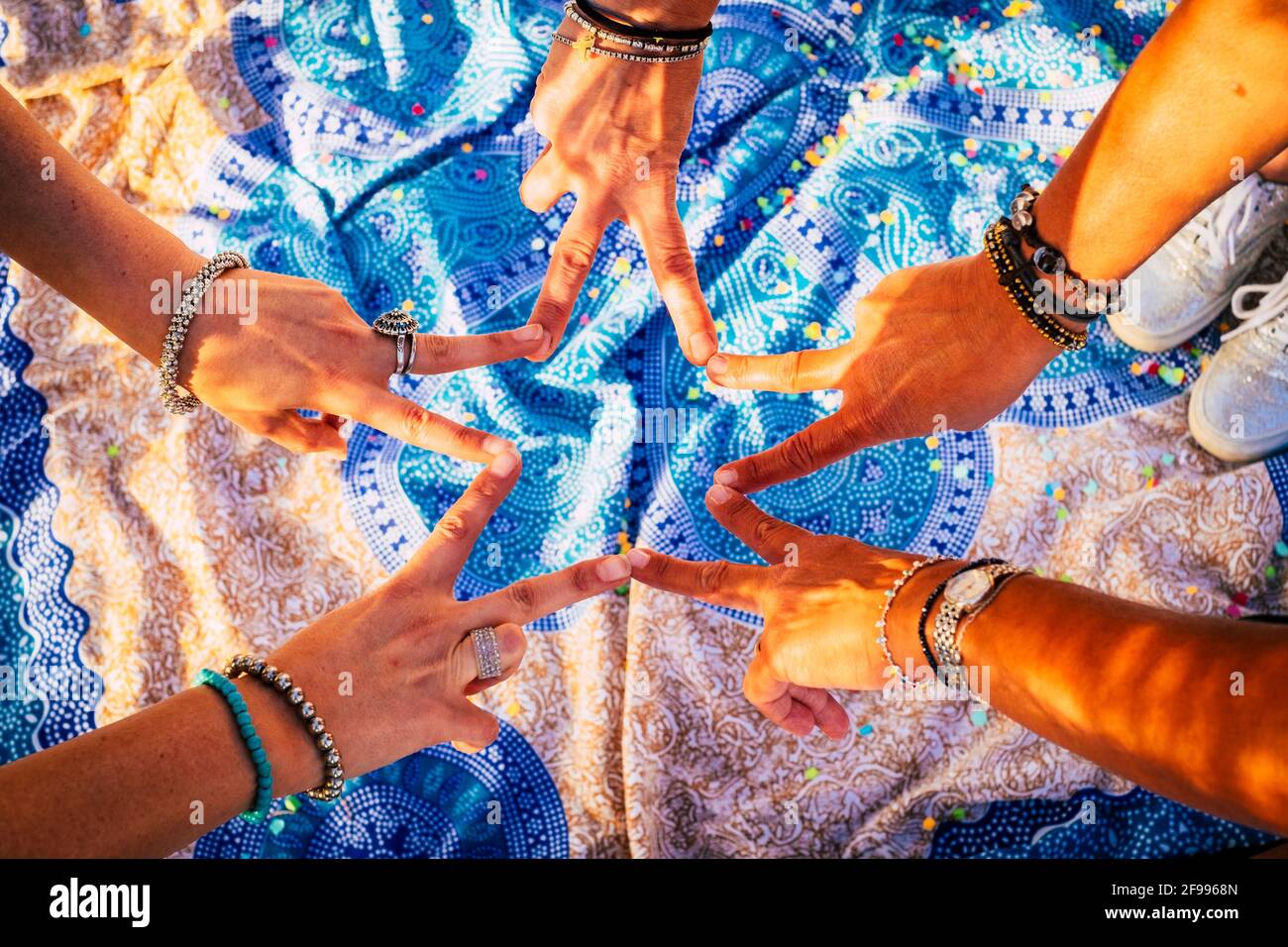 Close up top view of young people putting their hands together. Friends with stack of hands showing unity and teamwork - mandale outdoor background Stock Photo