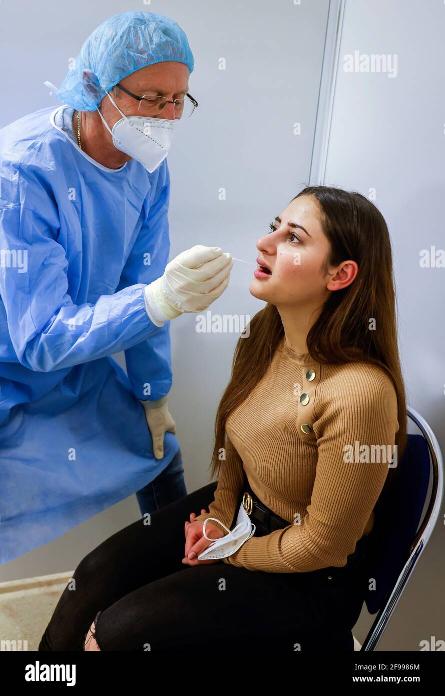 Essen, North Rhine-Westphalia, Germany - Corona test center Grugahalle open for free citizen test, Covid rapid test, a doctor tests a young woman for the corona virus using a throat swab, from March 8th, German citizens can have themselves tested for corona once a week free of charge in the rapid test center. Stock Photo