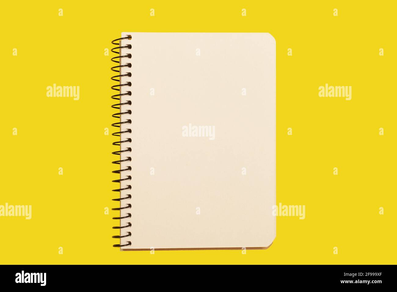 opened spiral notebook on a yellow surface Stock Photo