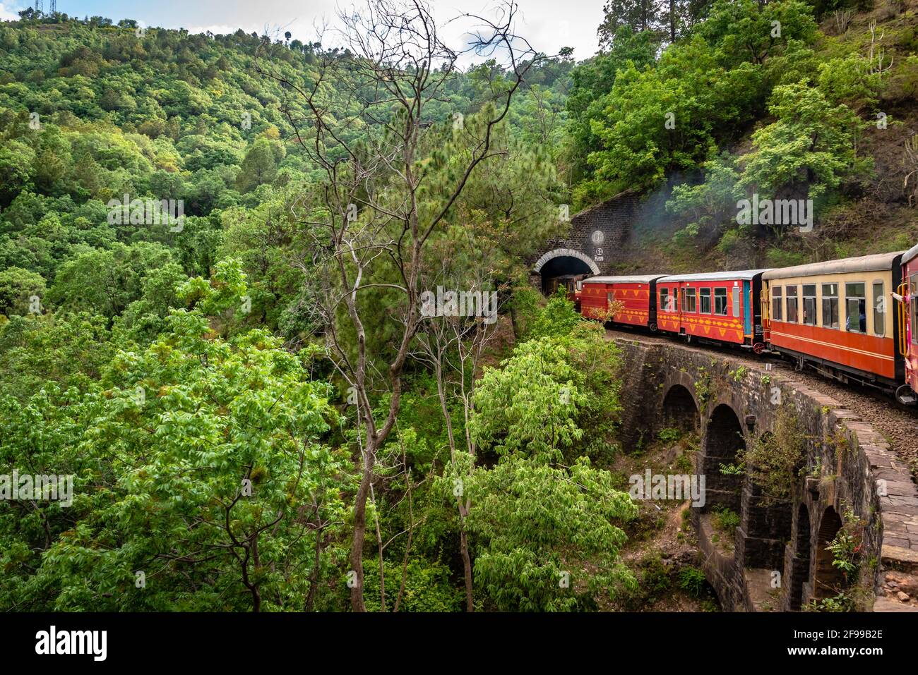 View from moving train on arch bridge over mountain slopes, beautiful view, one side mountain, one side valley. Toy train from Shimla to Kalka in Hima Stock Photo