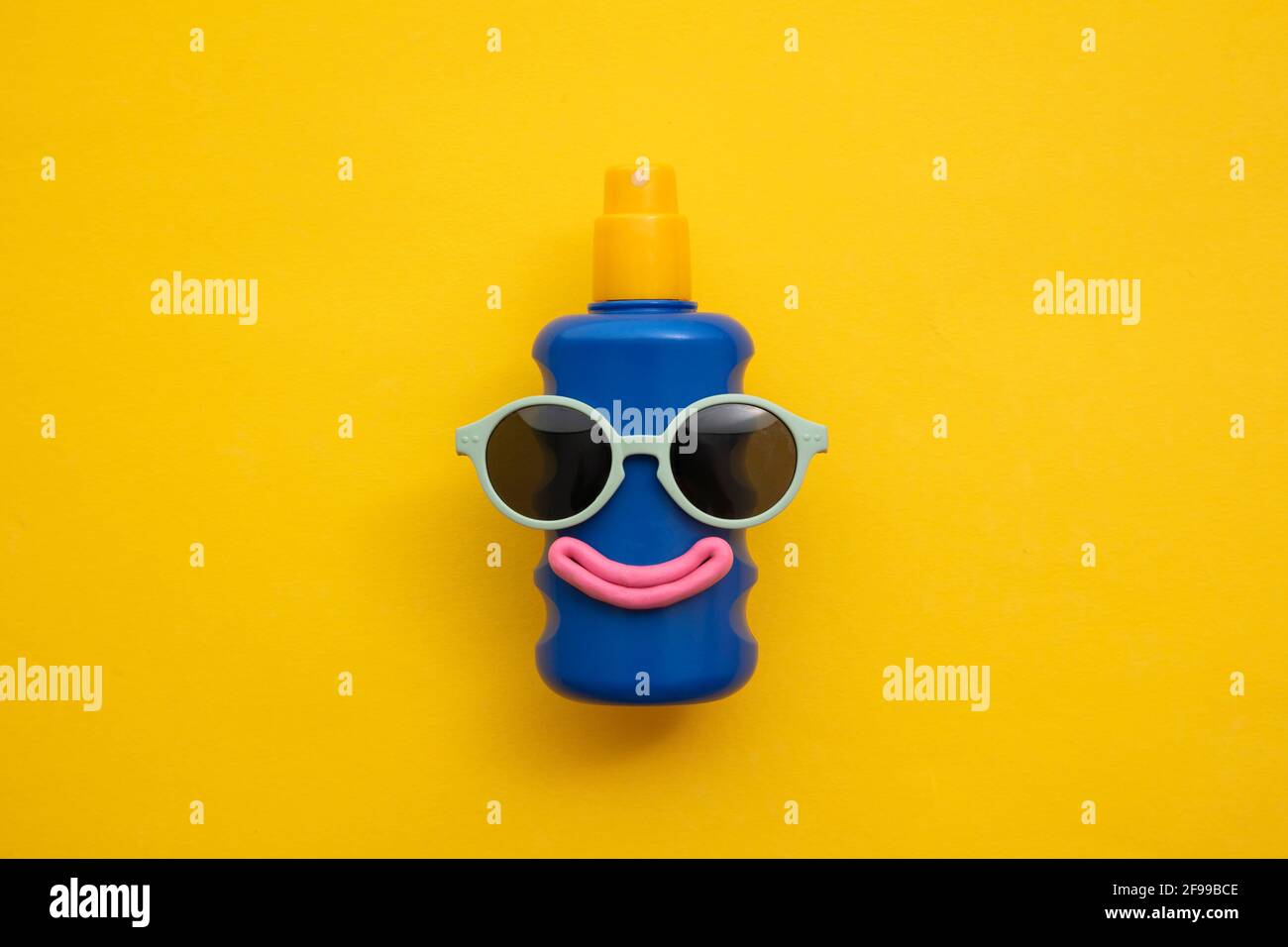 Happy sun block bottle wearing sunglasses and a smile on a yellow background Stock Photo