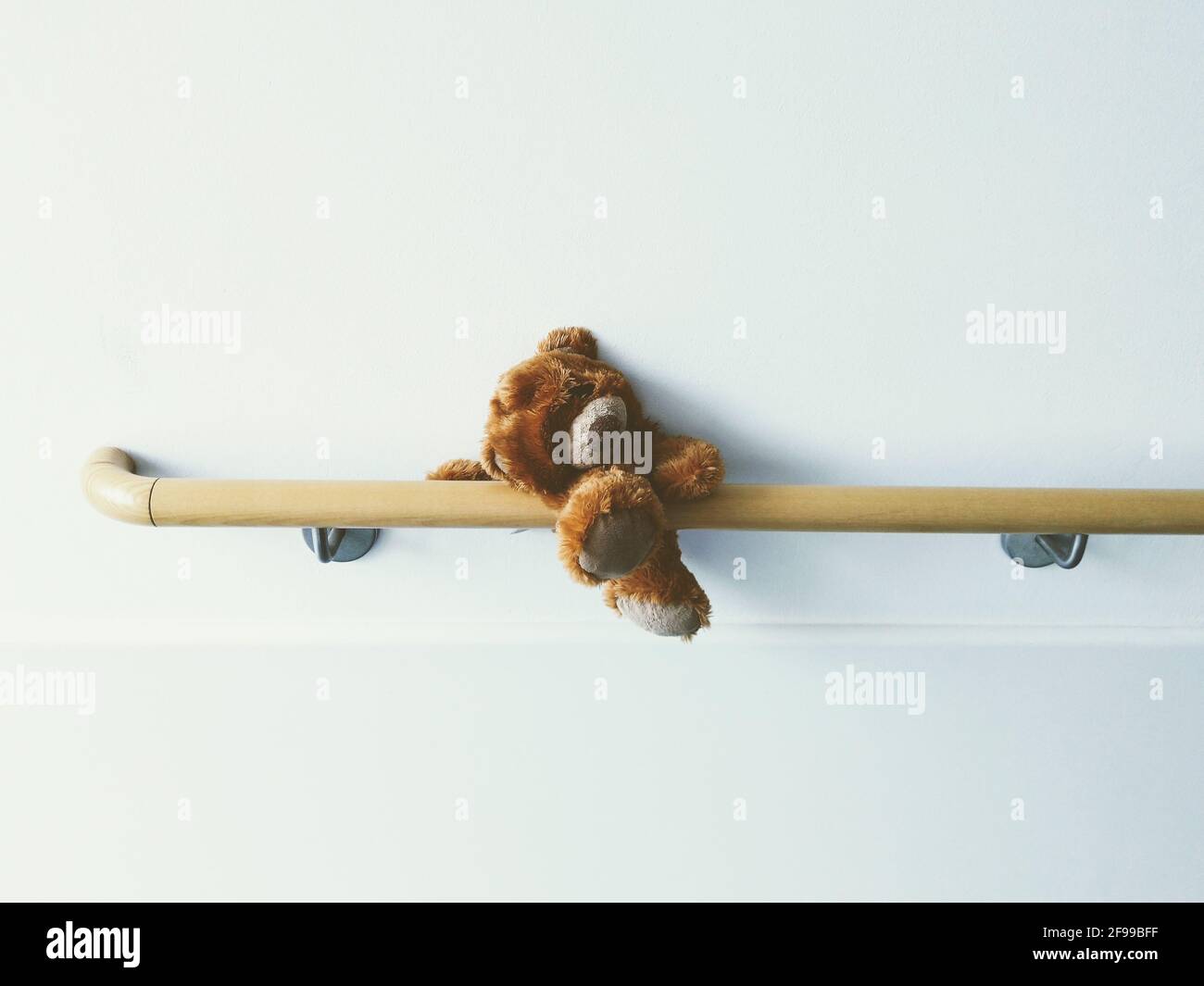 A forgotten, lone, lonely teddy bear is trapped on an armrest in the hospital. Stock Photo