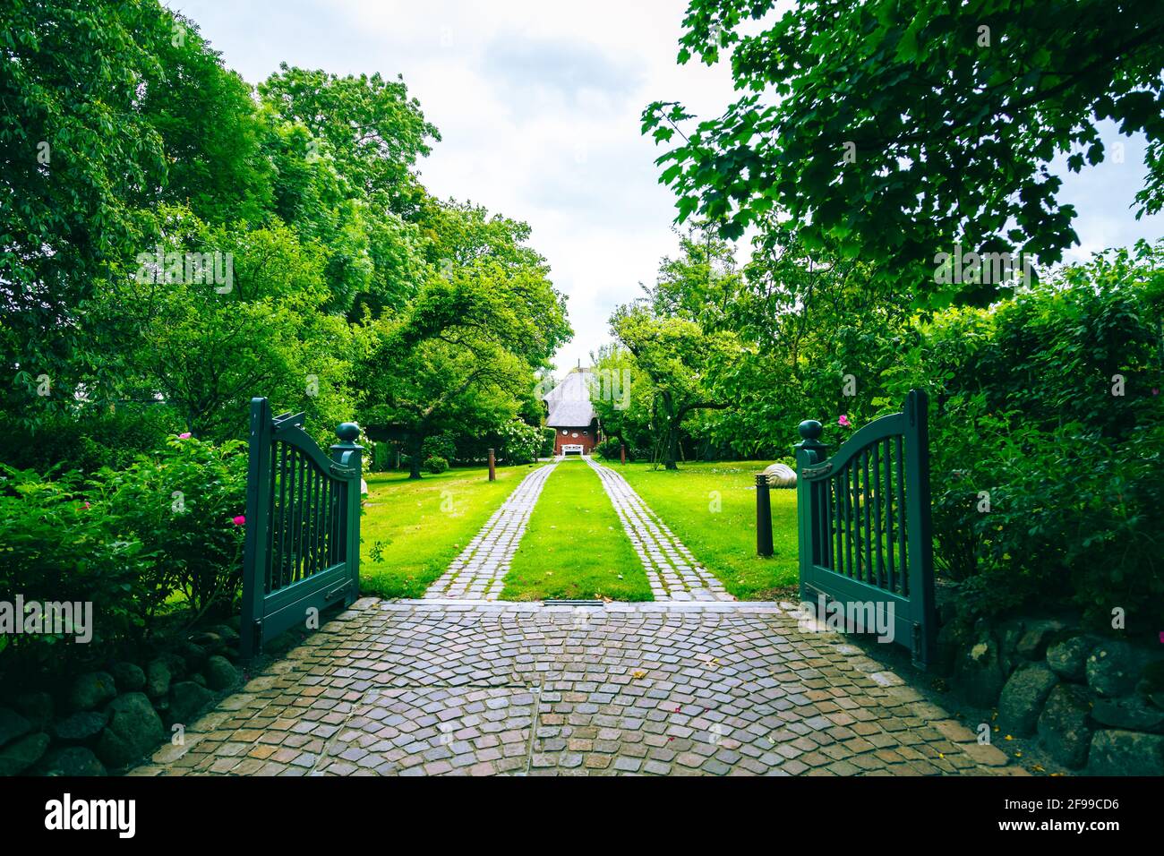 A garden gate and a long driveway to a house on Sylt. Stock Photo