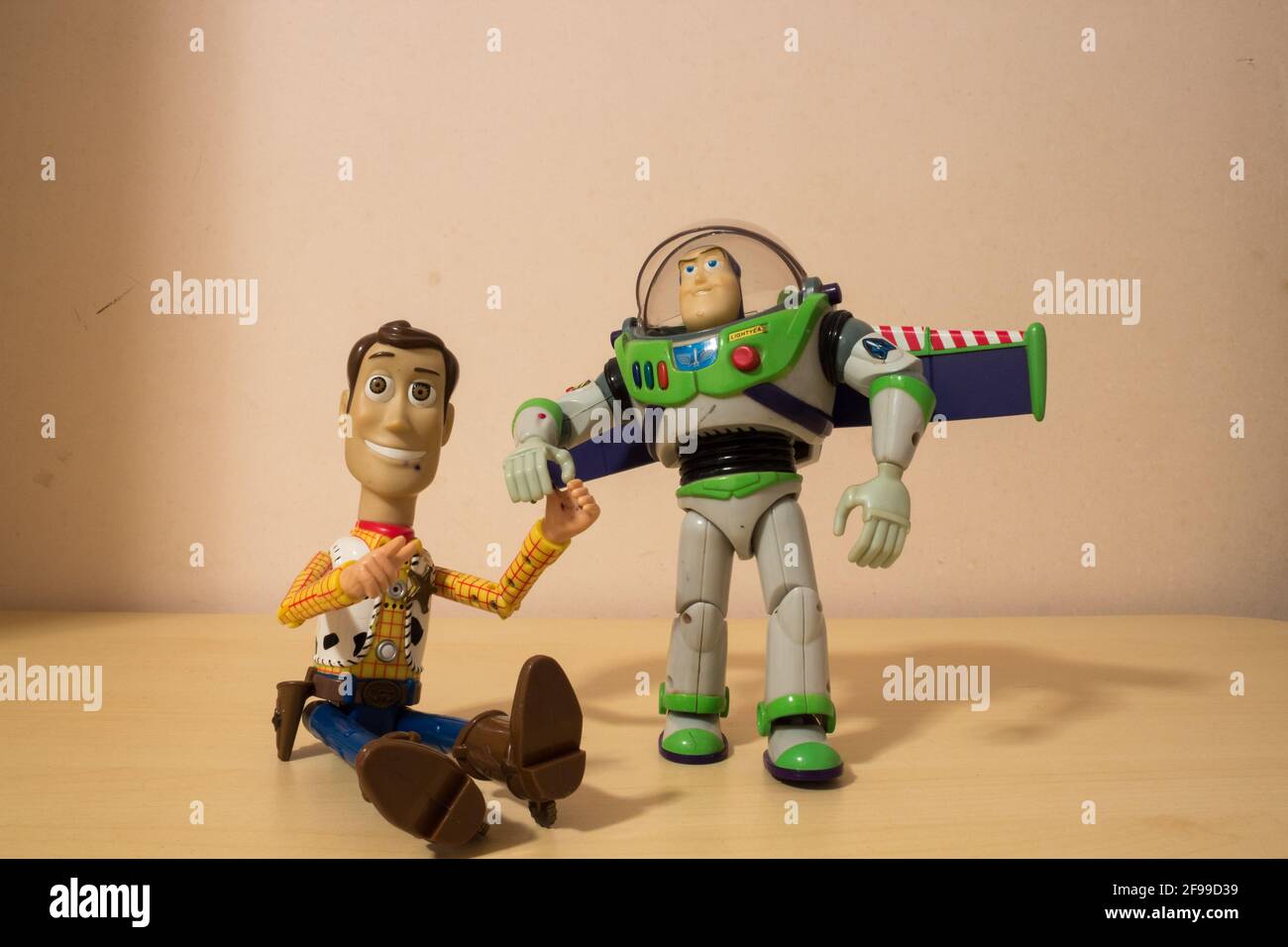 AVOLA, ITALY - Mar 21, 2021: Sheriff Woody and Buzz Lightyear toys, characters from Toy Story, laying close to each other holding their hands. Stock Photo