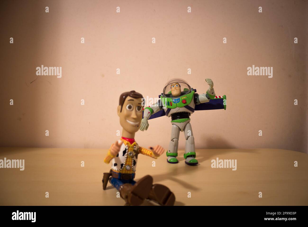 AVOLA, ITALY - Mar 21, 2021: Sheriff Woody and Buzz Lightyear toys, characters from Toy Story, laying close to each other on a wooden table. Buzz Ligh Stock Photo