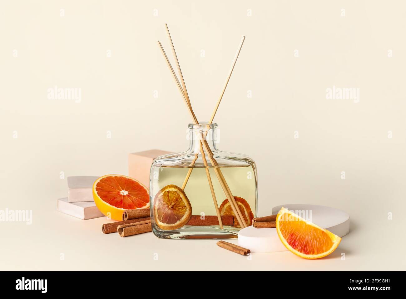 Reed diffuser with cinnamon and grapefruits on light background Stock Photo