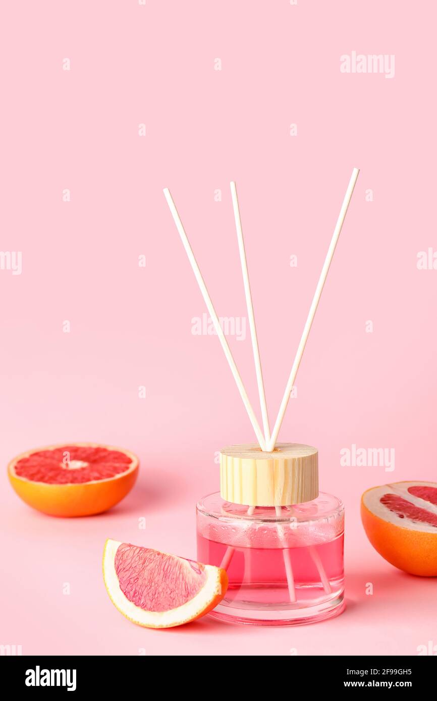 Reed diffuser with grapefruits on color background Stock Photo
