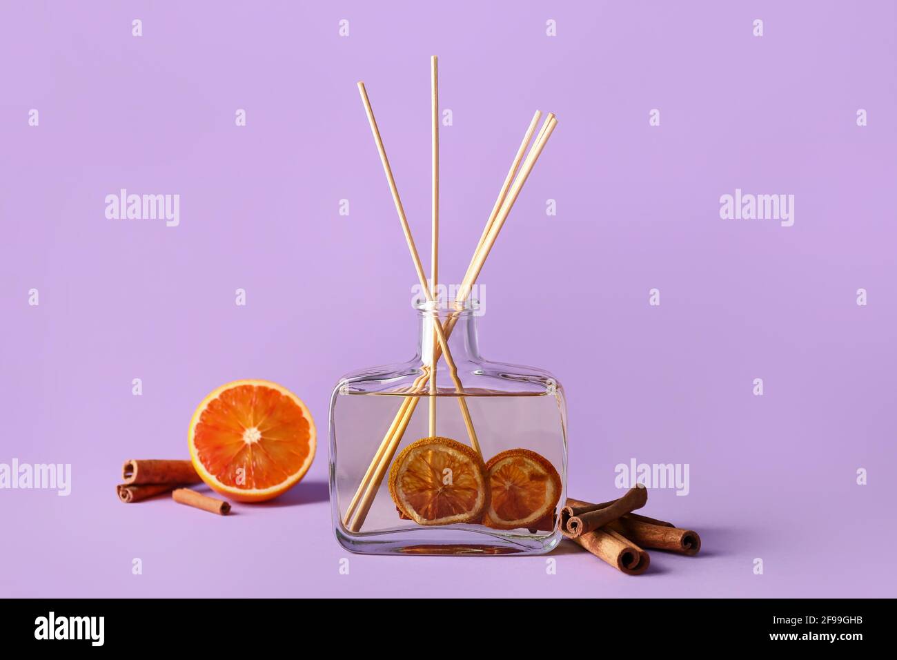 Reed diffuser with cinnamon and oranges on color background Stock Photo