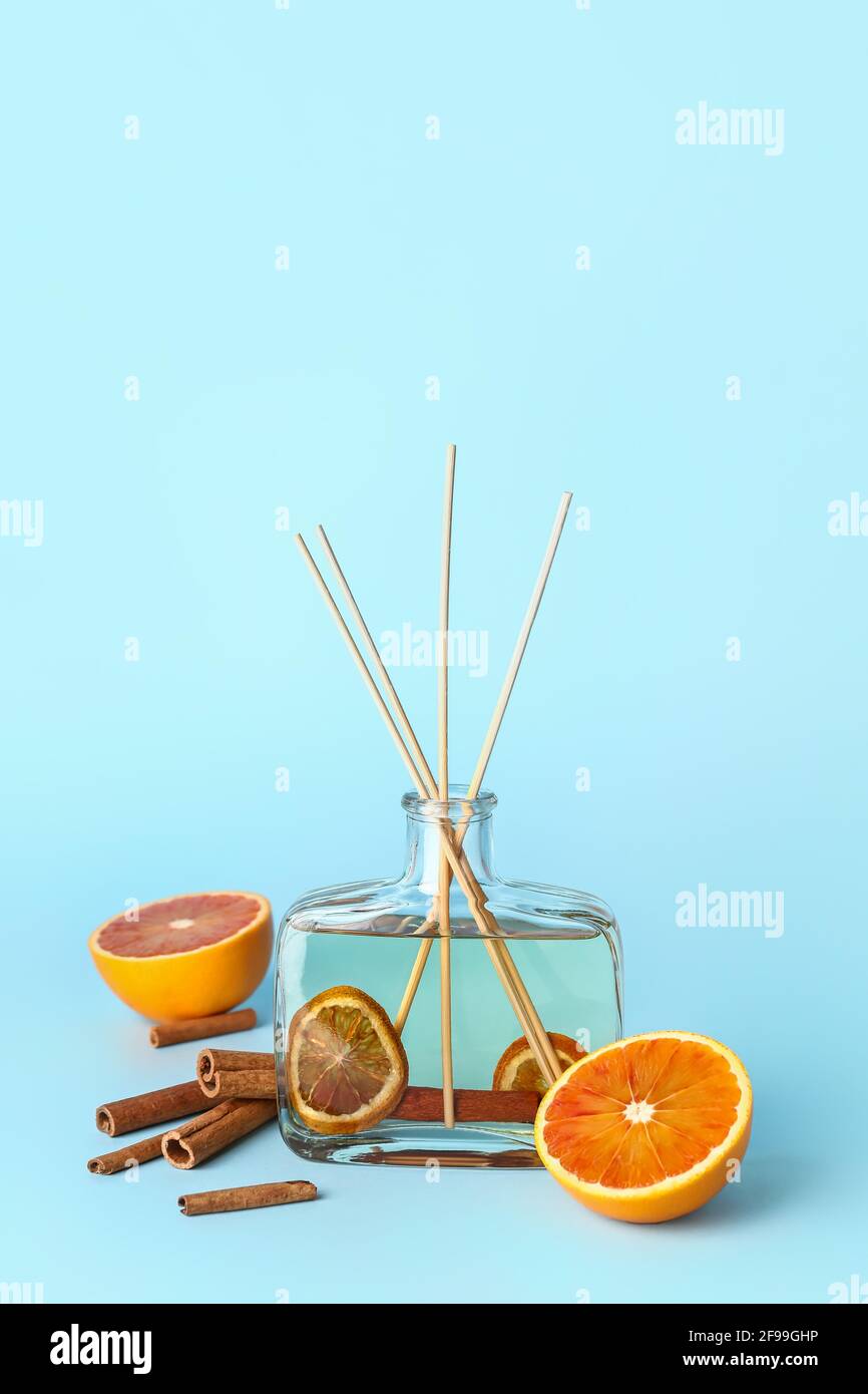 Reed diffuser with cinnamon and oranges on color background Stock Photo