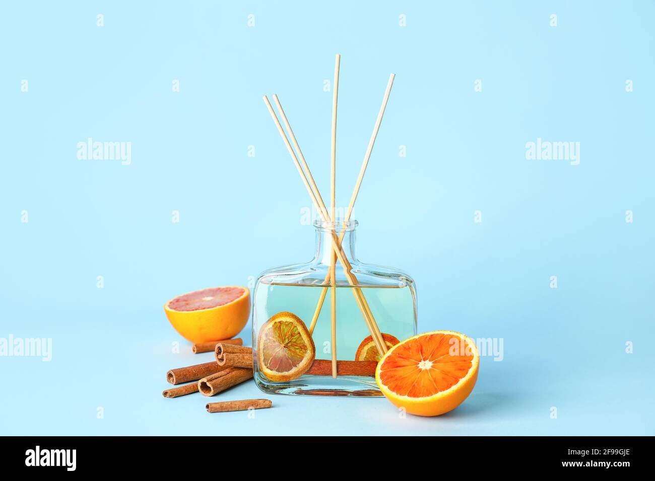 Reed diffuser with cinnamon and oranges on color background Stock Photo
